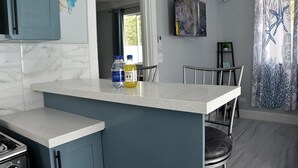 Une cuisine avec un îlot central, deux bouteilles d’eau et un coin repas avec des chaises.