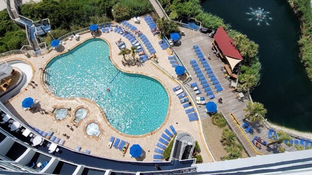 Ein Poolbereich mit mehreren Liegestühlen und einer zentralen Wasserspielen.