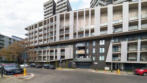 A modern multi-story building with a parking area in front. - Riverside Harmony Chic Apartment (Wrocław)