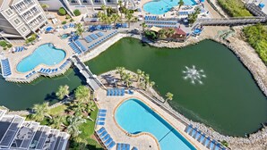 Ein Resort mit mehreren Schwimmbecken, Liegestühlen und einer Brücke, die verschiedene Bereiche verbindet.
