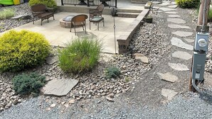 Une maison à deux étages dotée d’une terrasse, d’un espace salon extérieur et d’un chemin en pierre.