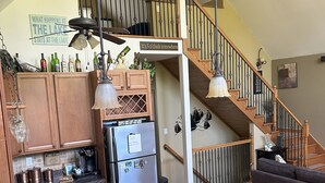 Une cuisine moderne dotée de plans de travail en granit, d’appareils électroménagers en acier inoxydable et d’un escalier en bois.