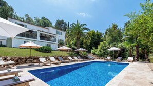 A rectangular swimming pool with clear blue water, surrounded by lounge chairs and umbrellas.