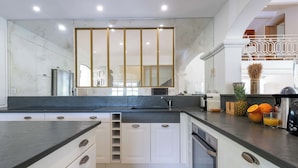 A modern kitchen with a central island, built-in appliances, and a large mirror above the sink.