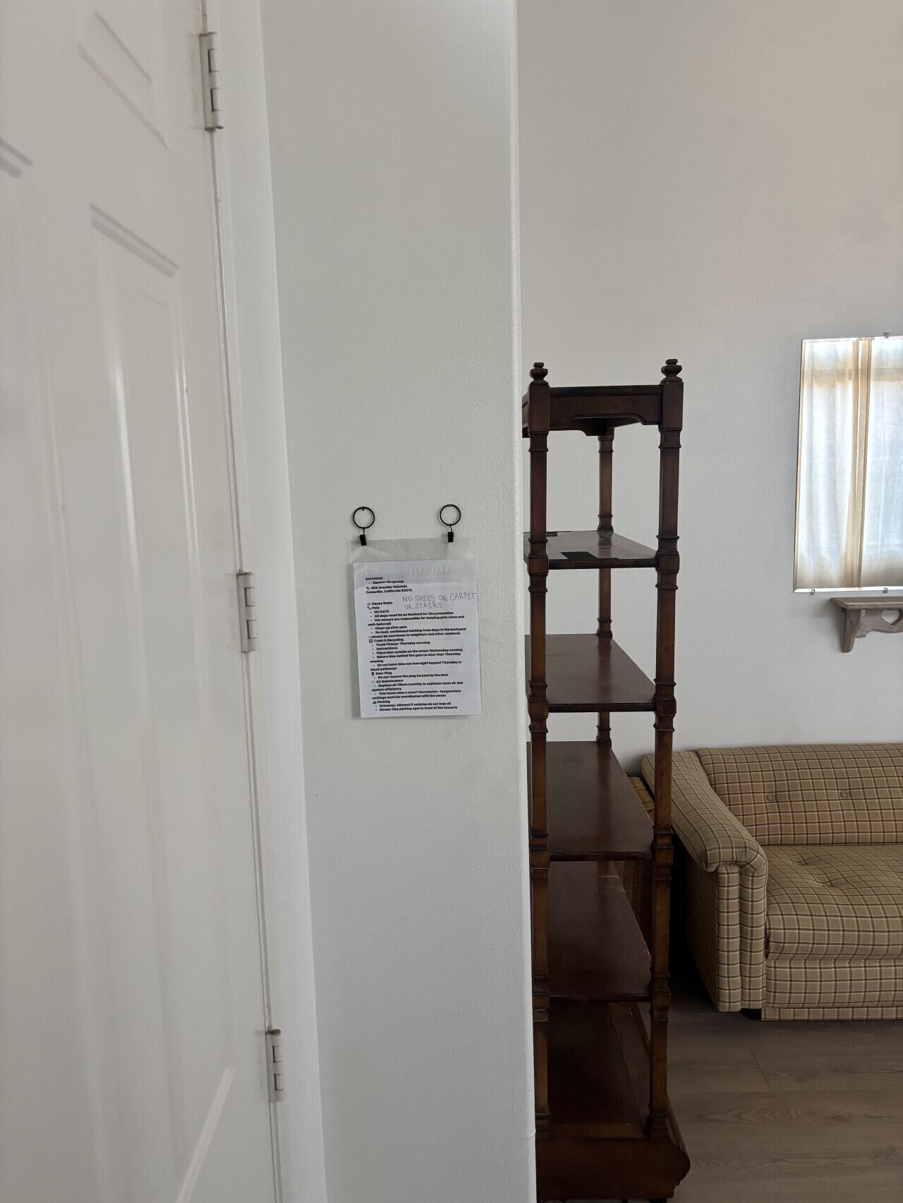 A room with a wooden chair, a sofa, and a door with a sign on the wall.
