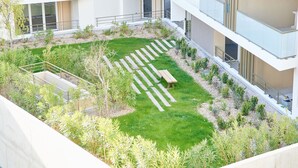 A modern building with a rooftop garden featuring a wooden bench, a small pond, and various plants. - Terra Tosca by Interhome (Fréjus)