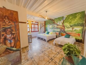 Una habitación con dos camas, un mural grande y vista a un bosque.