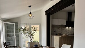 A dining area with a wooden table, white chairs, and pendant lighting. - Charming Canet House Close to the Beach and Amenities! (CANET PLAGE)