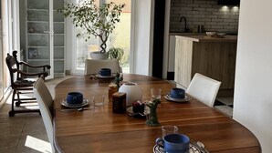 A modern dining area with a wooden table, white chairs, and pendant lighting. - Charming Canet House Close to the Beach and Amenities! (CANET PLAGE)
