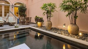 Un área de piscina interior con sillones reclinables, una mesa y plantas en macetas.