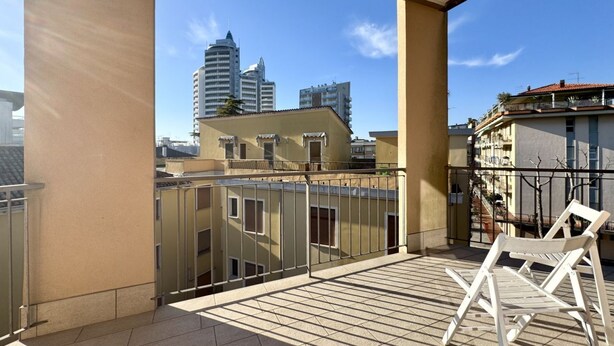 A balcony with a view of a cityscape, including high-rise buildings.