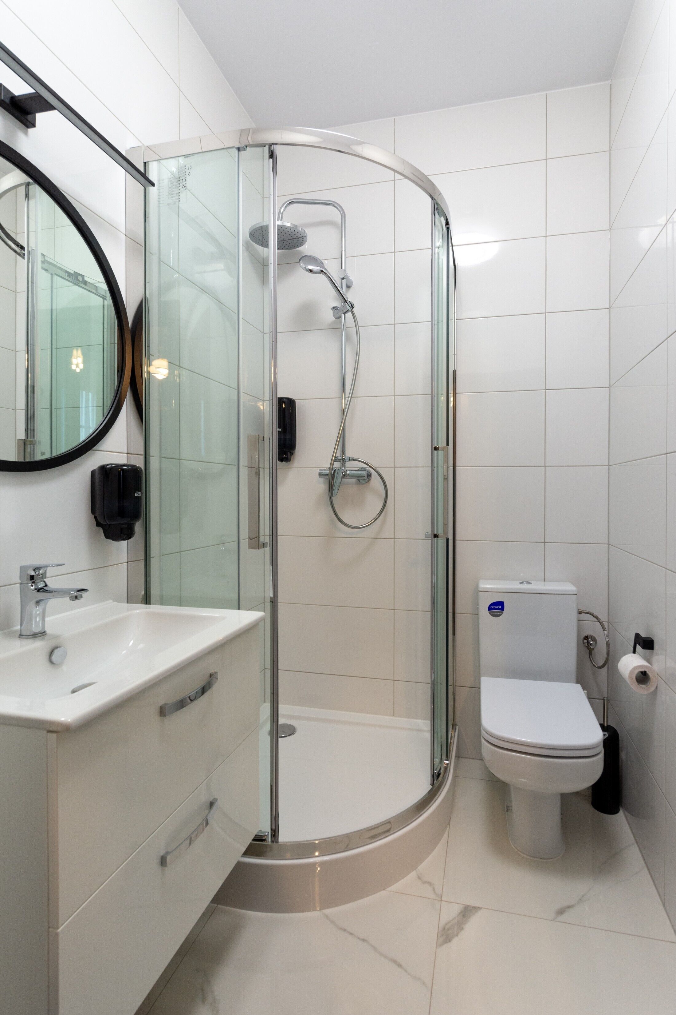 Un baño moderno con ducha envuelta en vidrio, un lavamanos blanco y un inodoro.