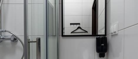 A modern bathroom with a glass shower enclosure, a white sink, and a mirror with a black frame.