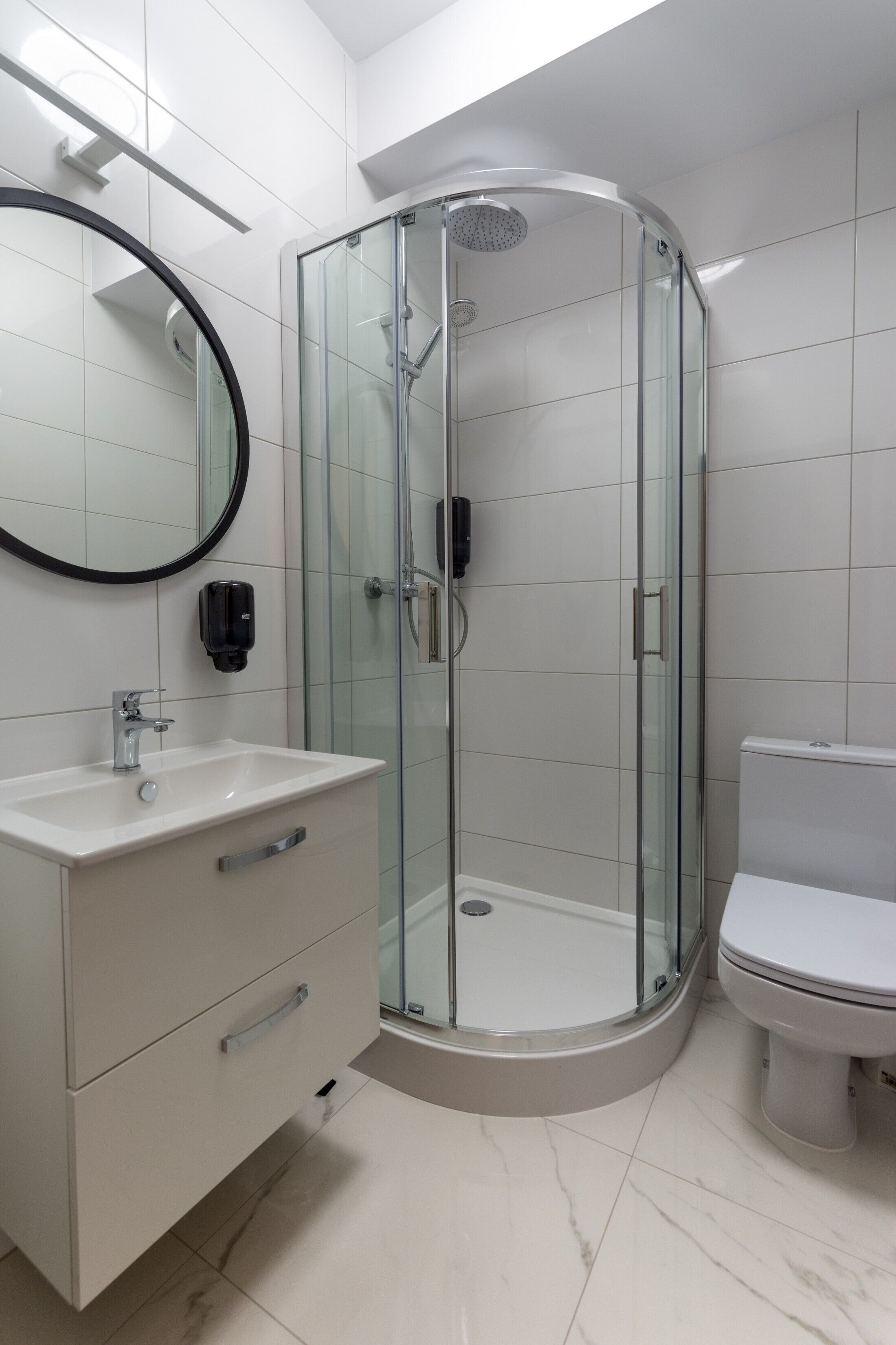 Une salle de bain moderne avec une douche à parois de verre, un lavabo blanc avec un miroir et des toilettes.