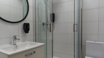 Une salle de bain moderne avec une douche à parois de verre, un lavabo blanc avec un miroir et des toilettes.