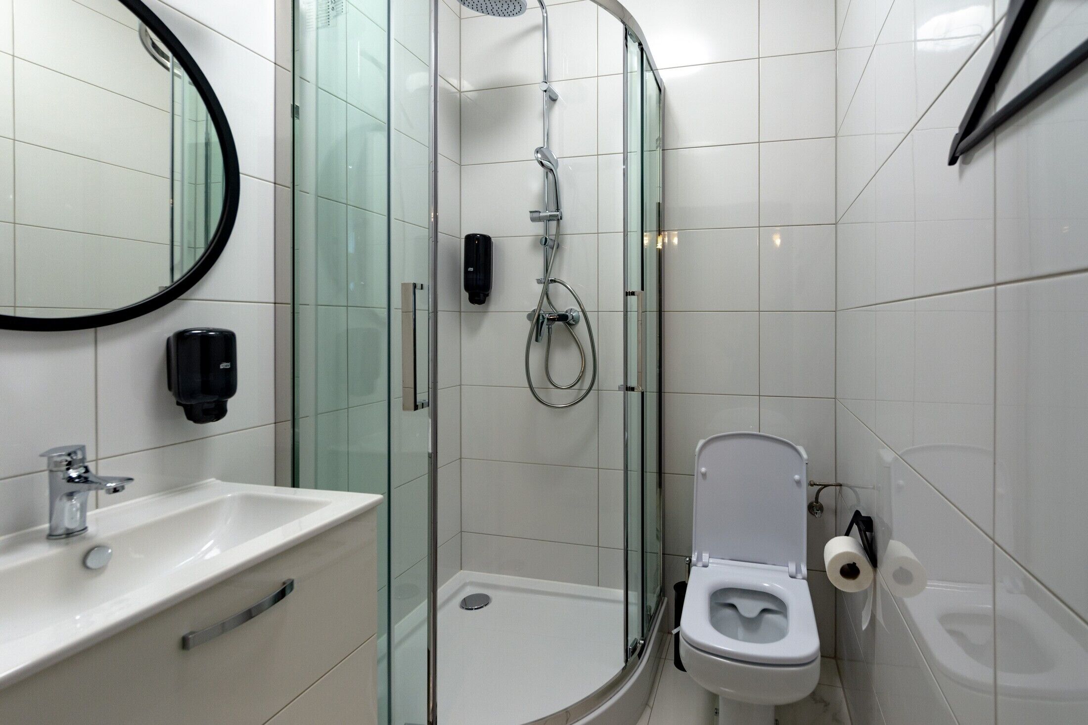 A modern bathroom with a glass-enclosed shower, a toilet, and a sink with a mirror.