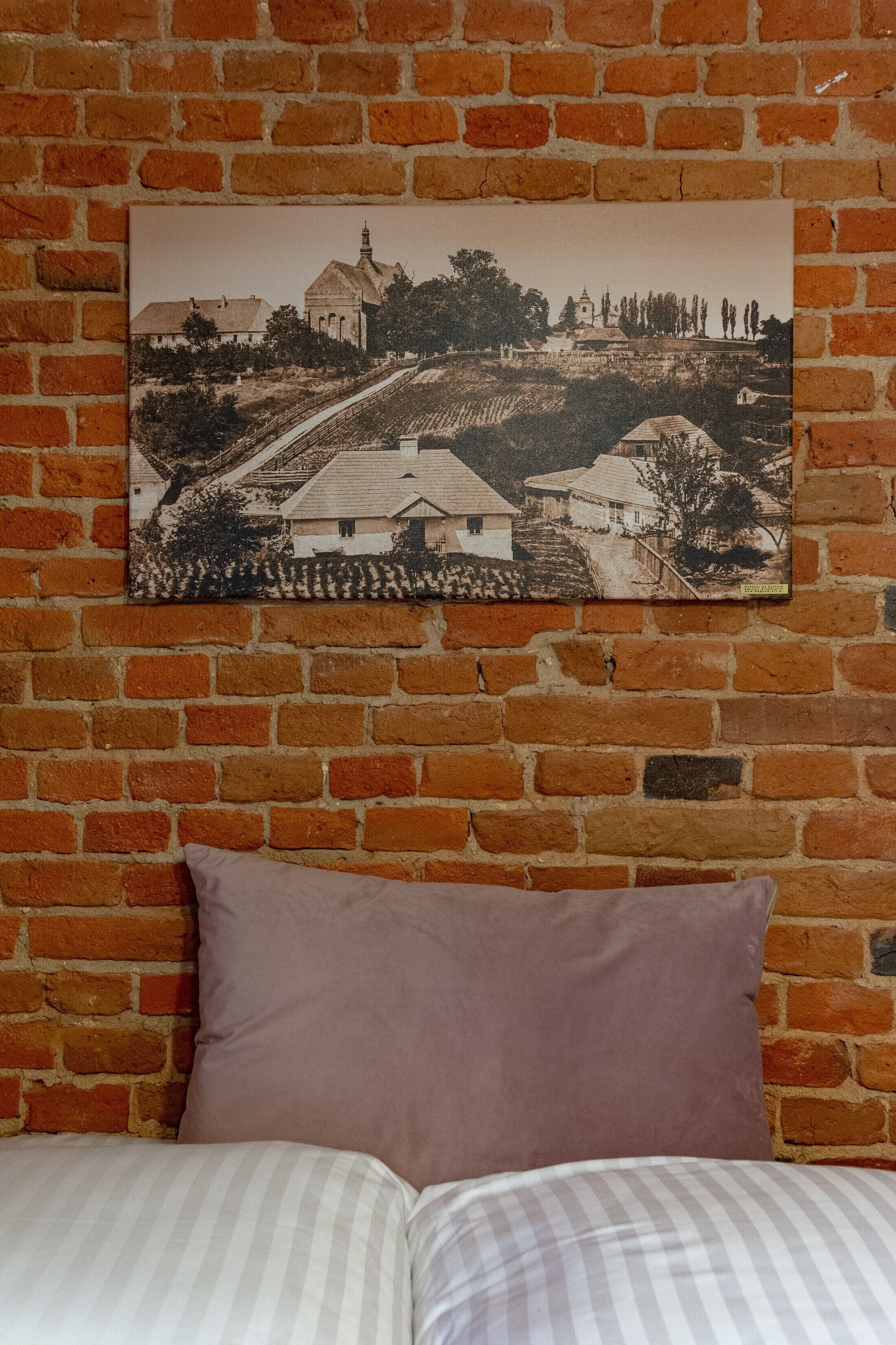 Una habitación con una pared de ladrillo y un cuadro enmarcado de un paisaje.