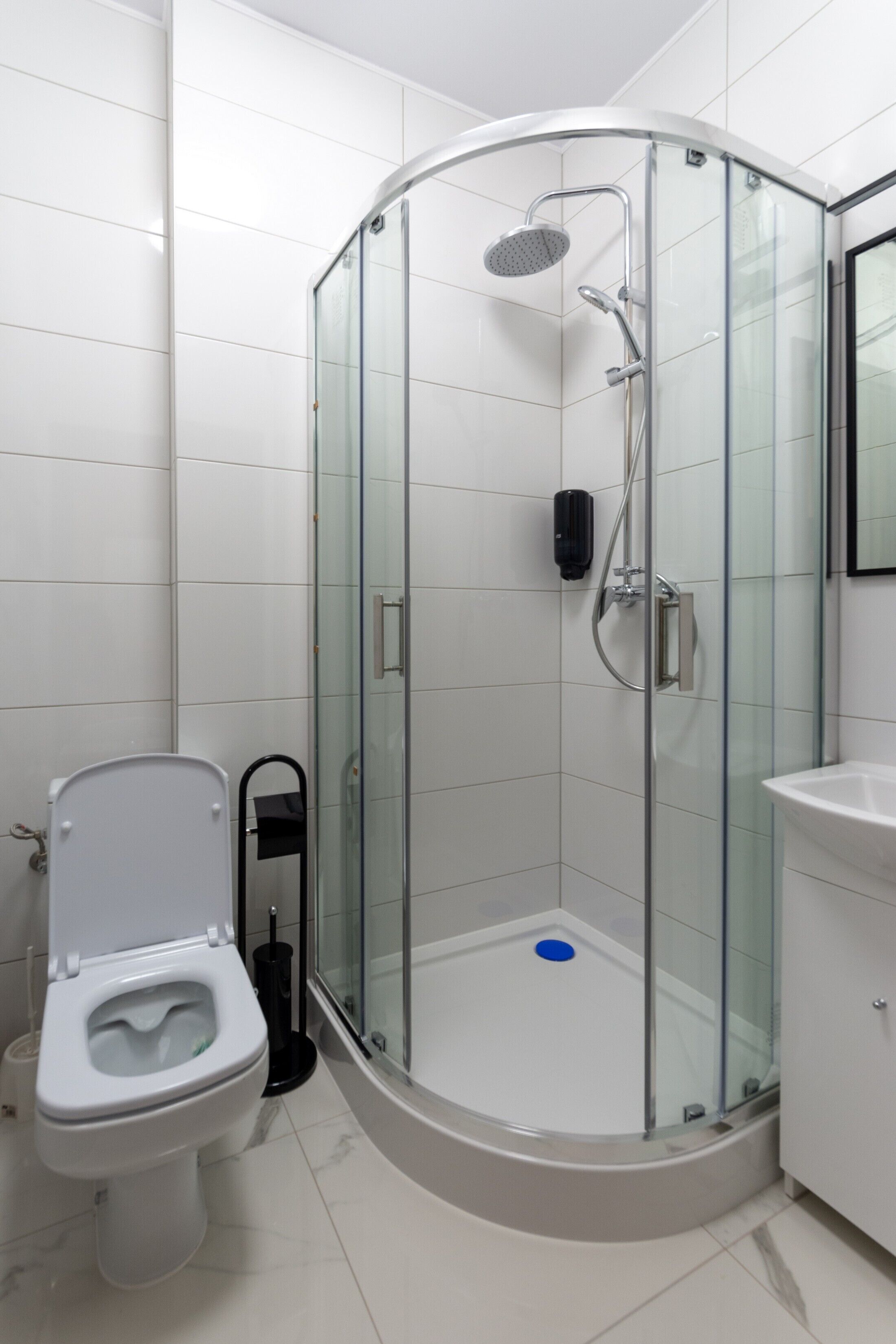 A modern bathroom with a glass-enclosed shower, a white toilet, and a sink.