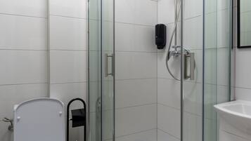 A modern bathroom with a glass-enclosed shower, a white toilet, and a sink.