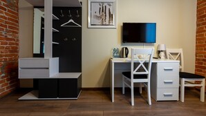 Une chambre moderne avec une armoire noire et blanche, un bureau avec une chaise, une télévision et une petite table avec une lampe.