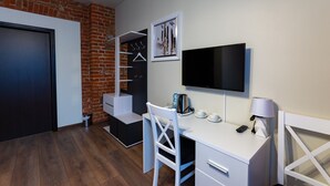 Une chambre moderne équipée d’un bureau, d’une chaise, d’une télévision et d’un mur en briques.