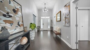 A hallway with a dark wood floor, a white door at the end, and a large abstract painting on the left. - Flexible Relocation Stay: Spacious, Pet-Friendly, w/ Utilities near Mid/Downtown (Atlanta)