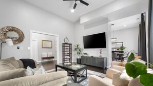 A modern living room with a sofa, coffee table, and a TV mounted on the wall. - Flexible Relocation Stay: Spacious, Pet-Friendly, w/ Utilities near Mid/Downtown (Atlanta)