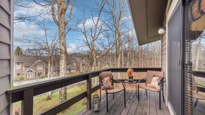 Une terrasse en bois avec une table et des chaises, un petit tapis et un objet décoratif.