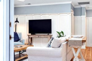 A living room with a television, a sofa, a coffee table, and a side table with a bowl. - Moon Dance Cottage – Family Retreat | Private Heated Pool | 1 Mile to Beach & Village (Saint Simons Island)