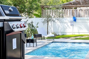 A backyard with a swimming pool, a grill, and outdoor furniture. - Moon Dance Cottage – Family Retreat | Private Heated Pool | 1 Mile to Beach & Village (Saint Simons Island)