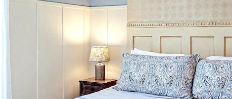 A bedroom with a bed, a nightstand with a lamp, and a patterned headboard.