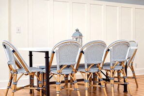 A dining area with a white table and four wicker chairs with blue and white patterns. - Moon Dance Cottage – Family Retreat | Private Heated Pool | 1 Mile to Beach & Village (Saint Simons Island)