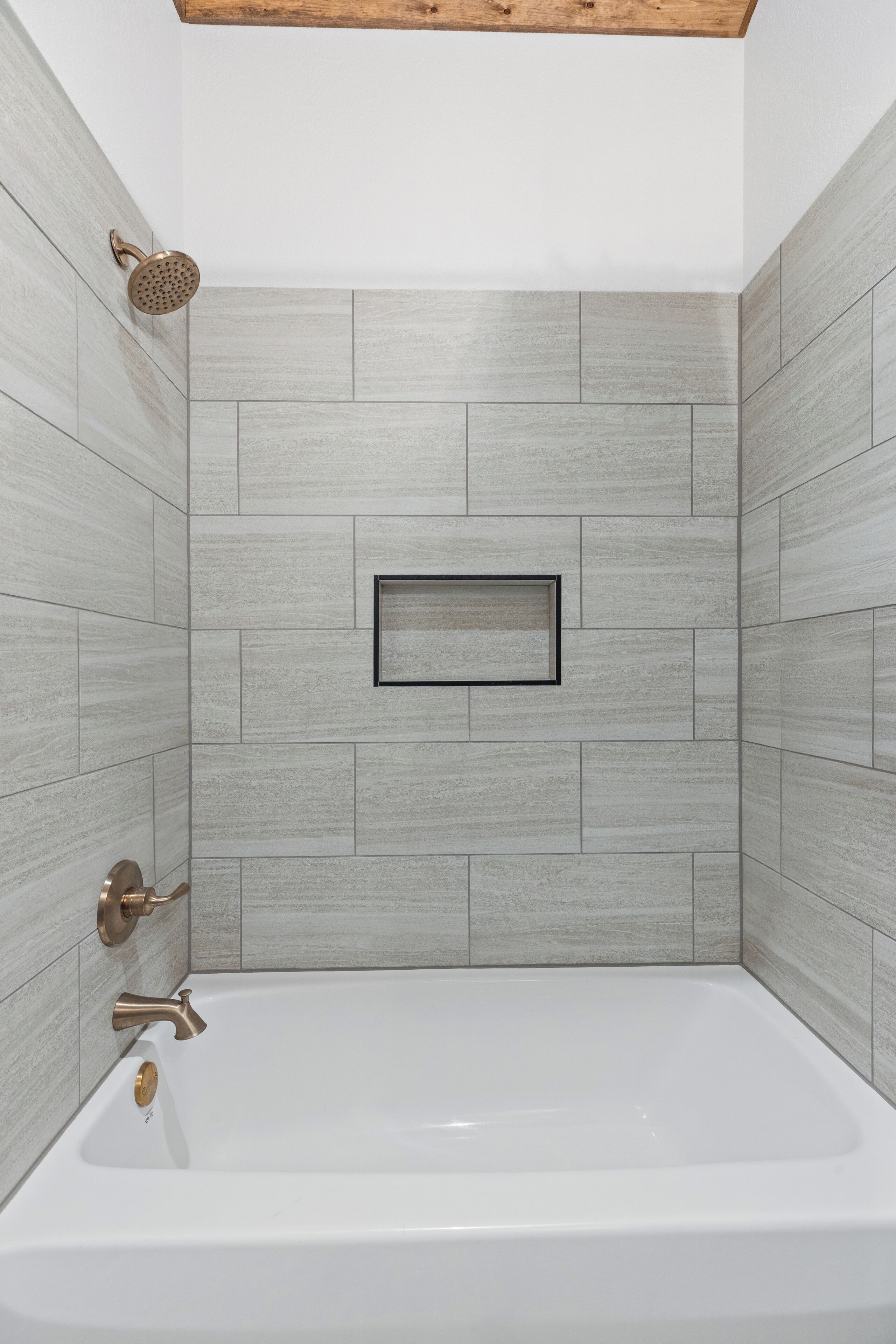 Ein modernes Badezimmer mit einer freistehenden Badewanne, einer Handbrause und einem gerahmten Bild an der Wand.