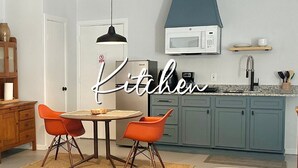Une cuisine moderne avec des meubles de couleur turquoise, un micro-ondes blanc et un coin repas avec des chaises orange.