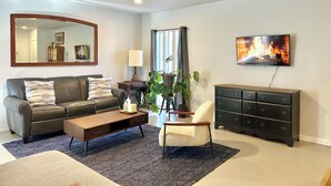 Un salon comprenant un canapé, une table basse, un fauteuil, un téléviseur et un ventilateur de plafond.