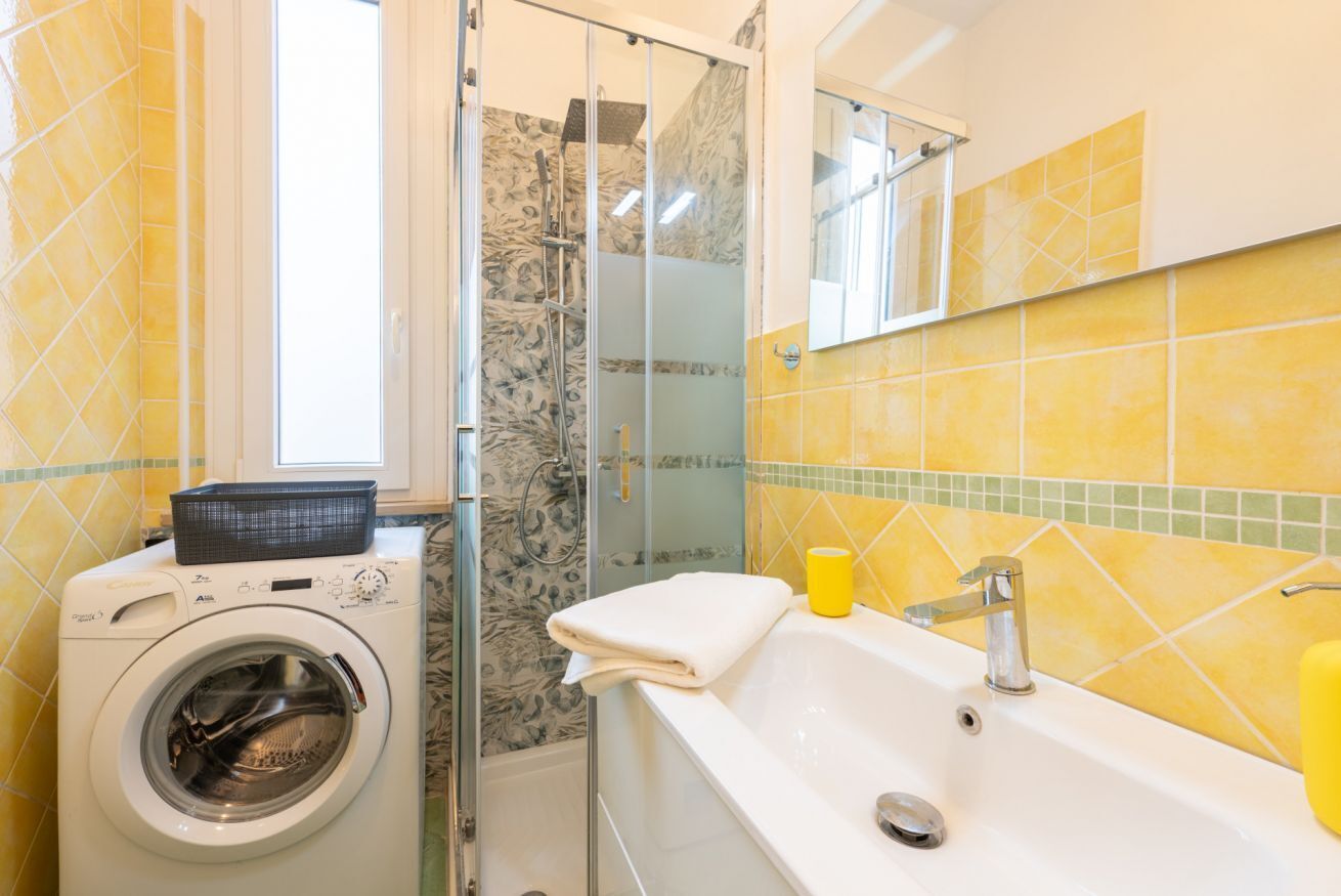 A bathroom with a washing machine, a bathtub, and a shower area.