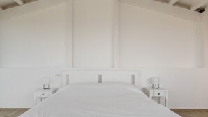 Ein Schlafzimmer mit einem Bett, zwei Nachttischen und einer weißen Wand.