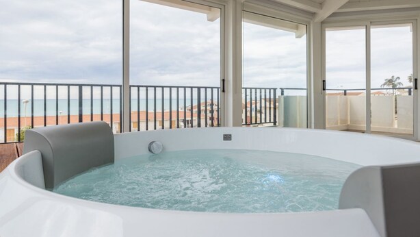 Ein Whirlpool auf einem Balkon mit Blick auf Strand und Meer.