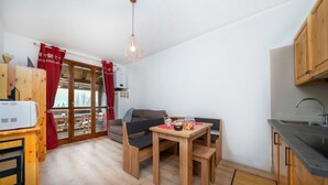 Een compacte keuken met een eethoek, houten keukenkastjes en een ingebouwde oven.