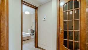 Un corridoio che conduce a una camera da letto con un letto, una sedia e un tavolino.