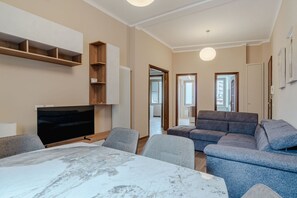 Ein modernes Wohnzimmer mit Flachbildfernseher, einem Marmortisch, grauen Sofas und eingebauten Holzbögen.