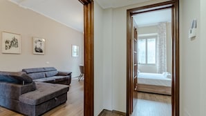 Una stanza con un divano, un letto, pavimento in legno e una porta che dà su un'altra stanza.