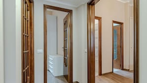 Un corridoio con porte in legno e una scala bianca.