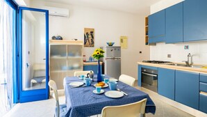 Una cocina moderna con armarios azules, una mesa de comedor dispuesta con platos y tazas, y un refrigerador.
