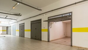 Un espacio interior amplio con pisos de baldosas, un techo alto con tuberías a la vista y una franja amarilla en las paredes.