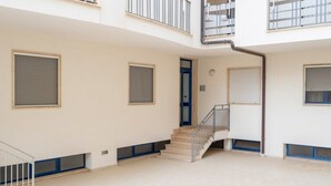 Un edificio residencial de varios niveles con una escalera central, balcones y grandes ventanales.
