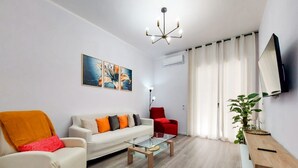 Una sala de estar moderna con un sofá, un sillón, una mesa de centro y un televisor montado en la pared.