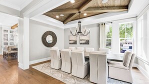 Zona pranzo con soffitto in legno, un lampadario e vista sull'esterno.