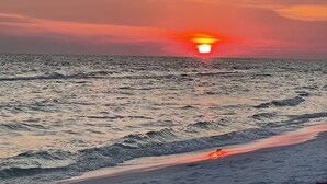 Tramonto sull'oceano con le onde che si infrangono sulla spiaggia.