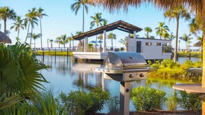 A waterfront property with a grill, palm trees, and a house with a covered patio. - Pointe Santo A4 - Gulf front ground level 3br, setting the standard for beachfront luxury. (Sanibel)